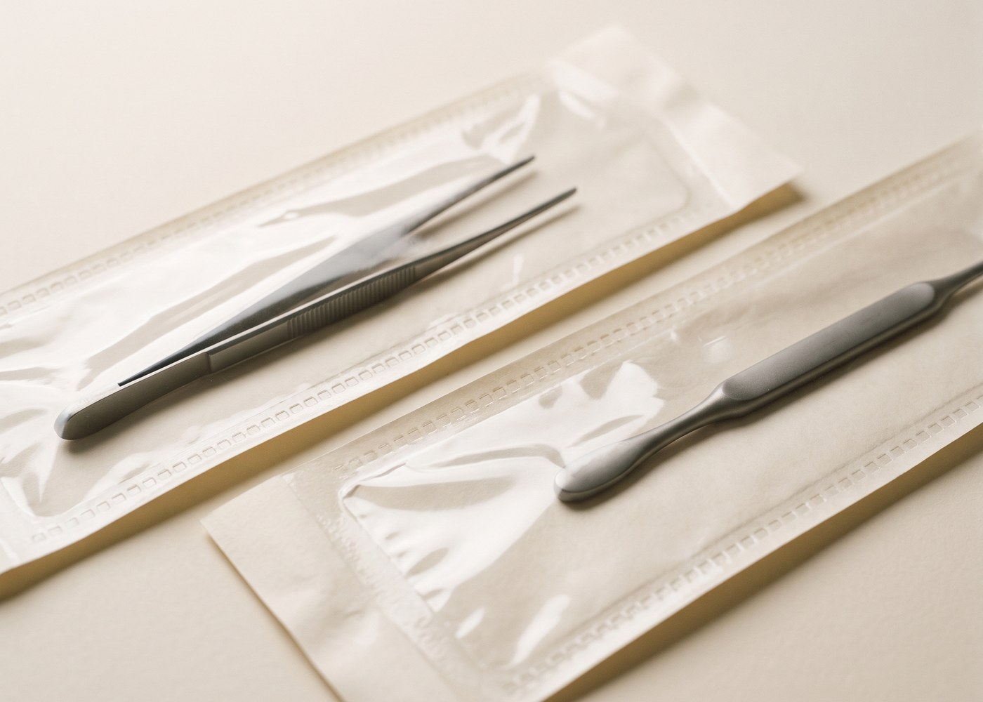 Zwei steril verpackte Instrumente in Papierbeuteln mit Sichtfenster auf hellem Grund