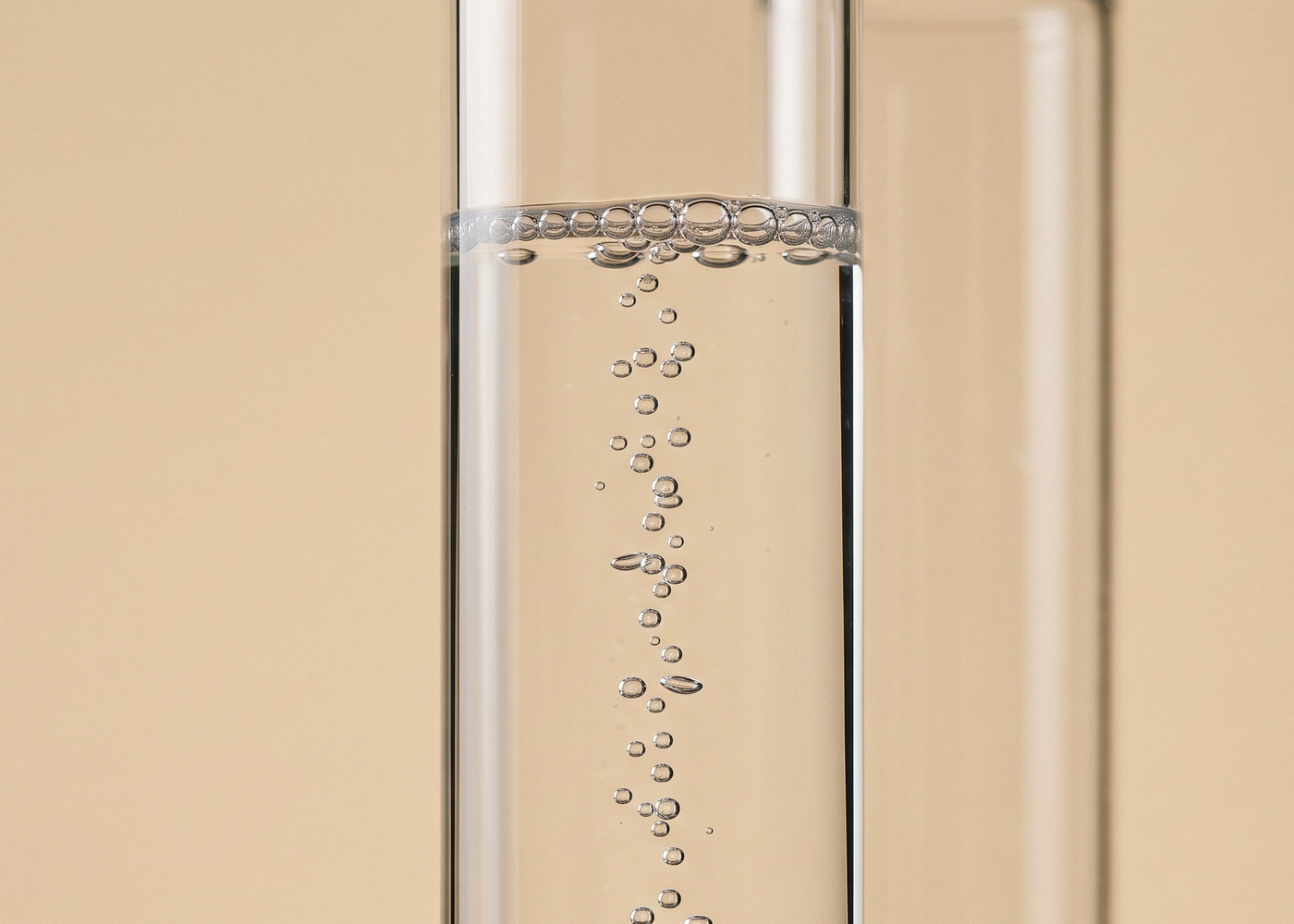 Glaszylinder mit klarer Lösung, in der eine feine Säule kleiner Bläschen aufsteigt