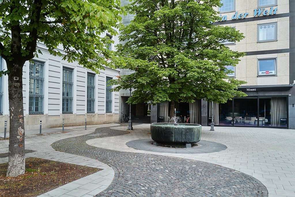 Der Bierbrunnen auf dem kleinen Platz vor dem Brauerhaus, dahinter das Schaufenster von Minotti