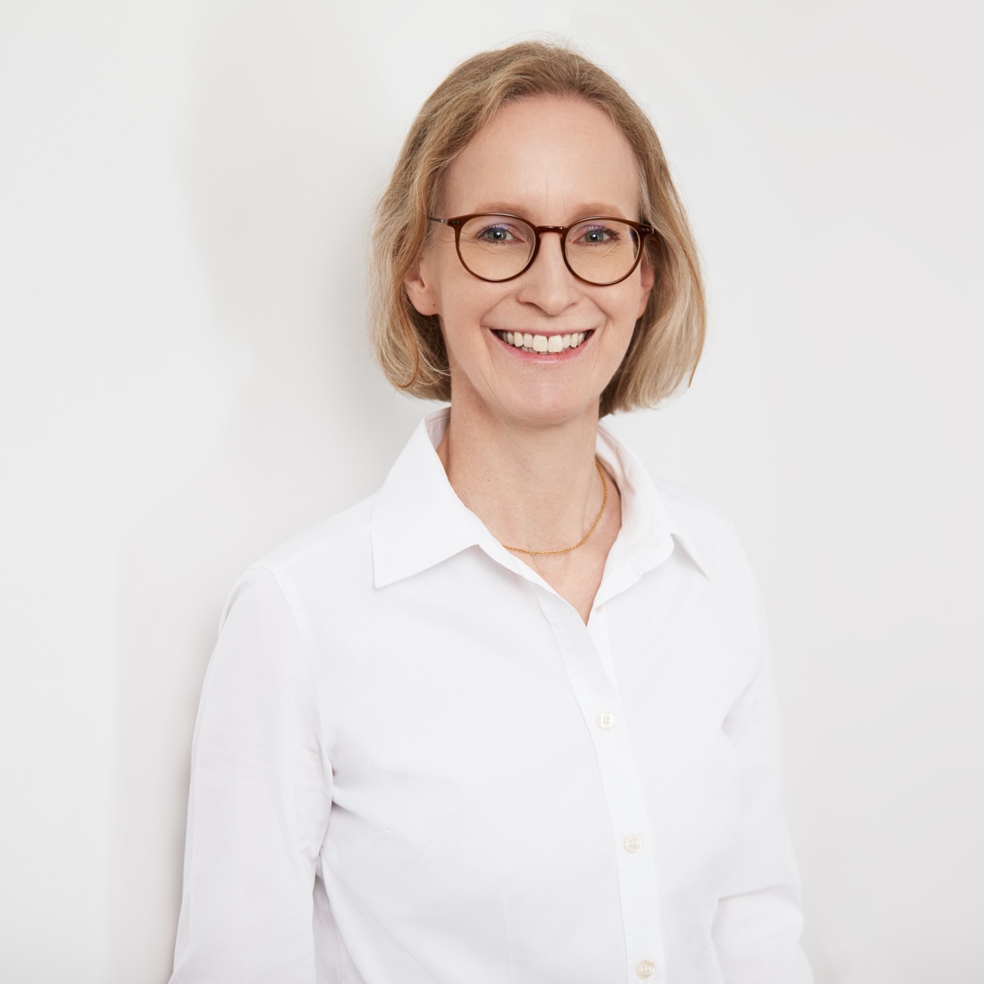 Dr. med. Regina Ramesohl in weißer Bluse, lächelnd vor heller Wand